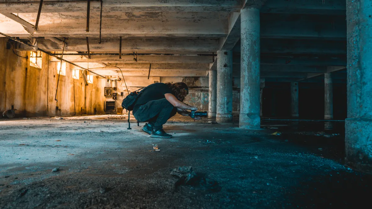 person crouching in a dark unfinished crawl space